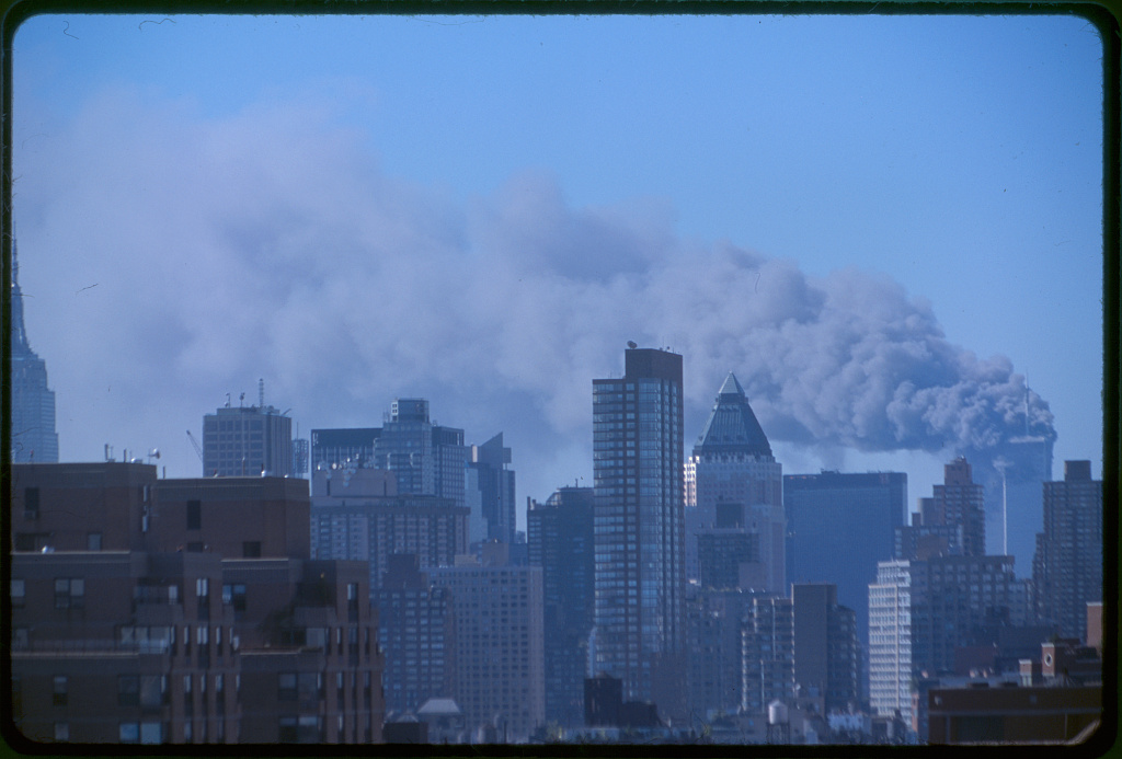 New York City skyline with smoke rising from buildings during daytime.