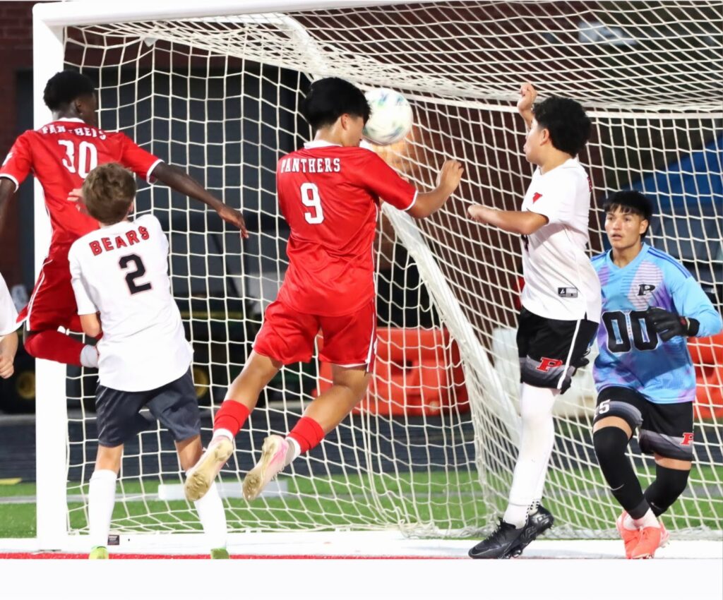 Young soccer players in action during a game near the goalpost.