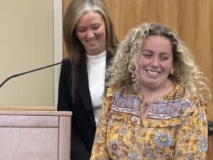 Two women smiling at a downtown planning meeting, discussing urban development.
