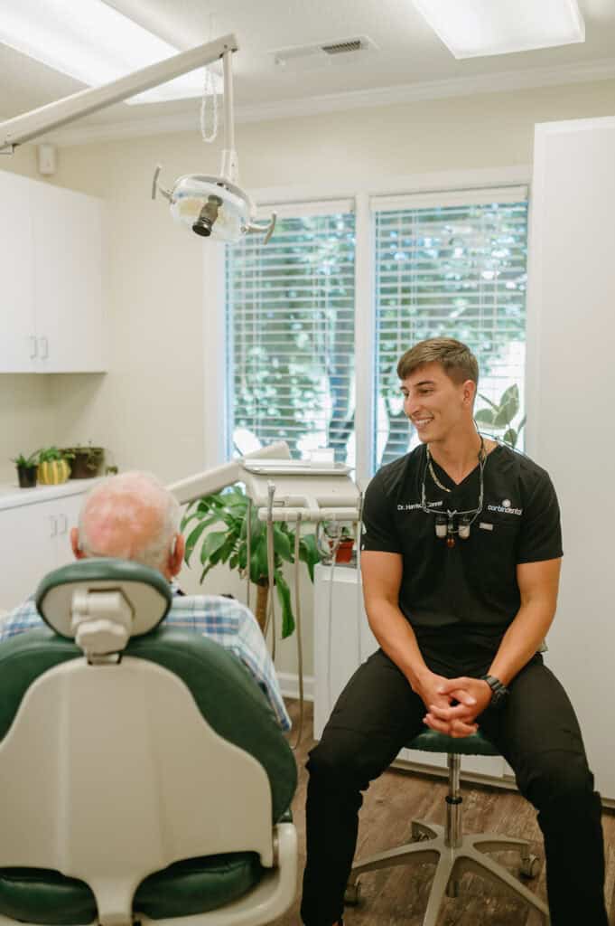 Young male dental professional consulting with elderly patient in clinic.