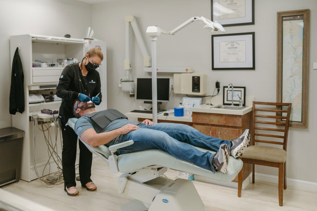 Dental professional performing a procedure on a patient in a clinic room.