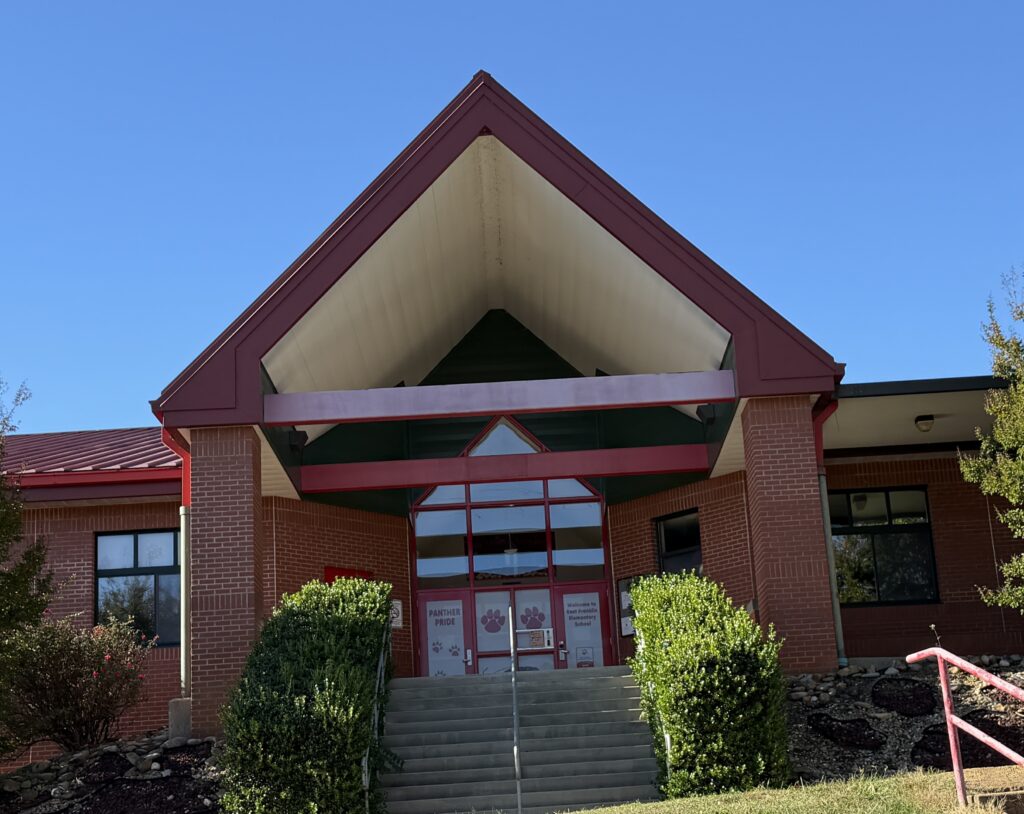 East Franklin school building with brick facade and prominent entrance under a blue sky.