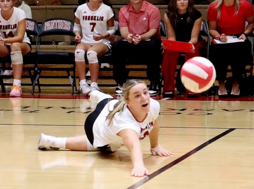Girl diving for volleyball during a game at Macon Sense sports event.