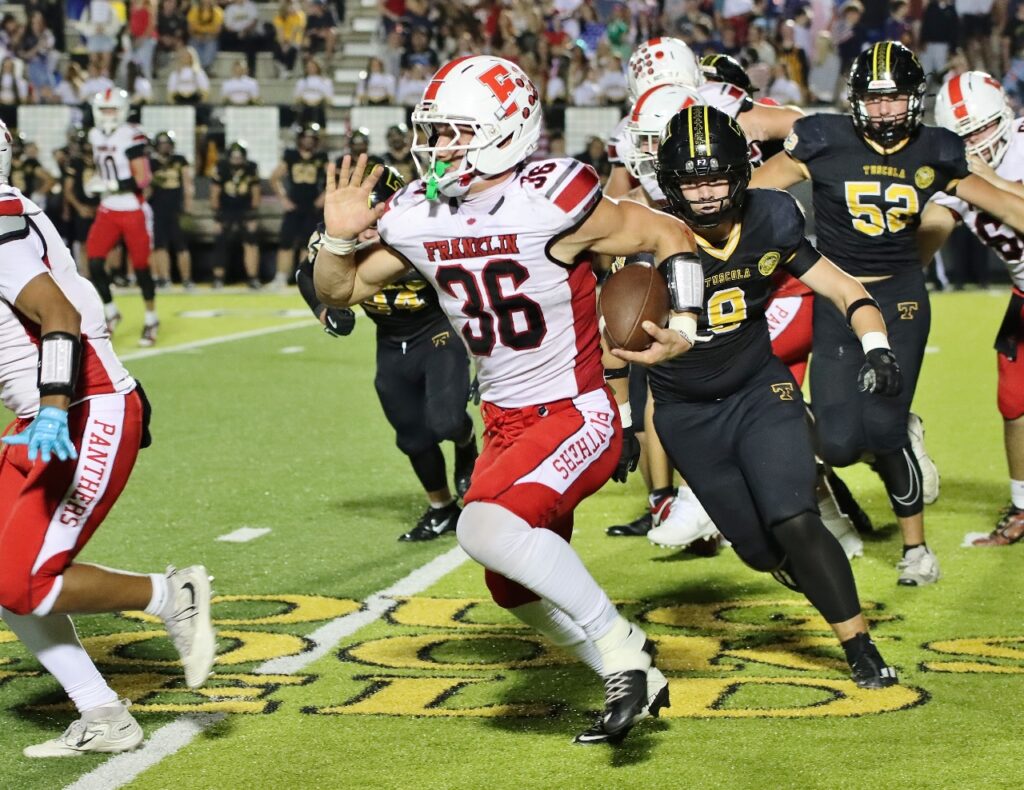 Football player in white jersey running with ball during game.