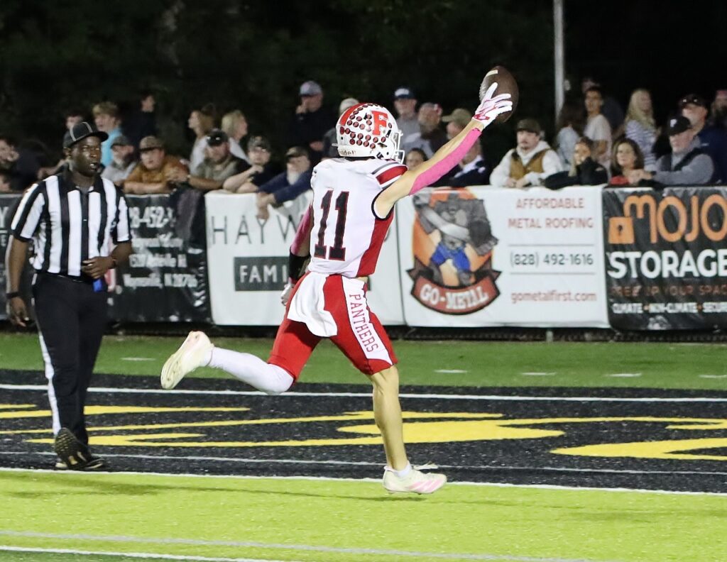 Football player catching the ball in a game with spectators in the background.