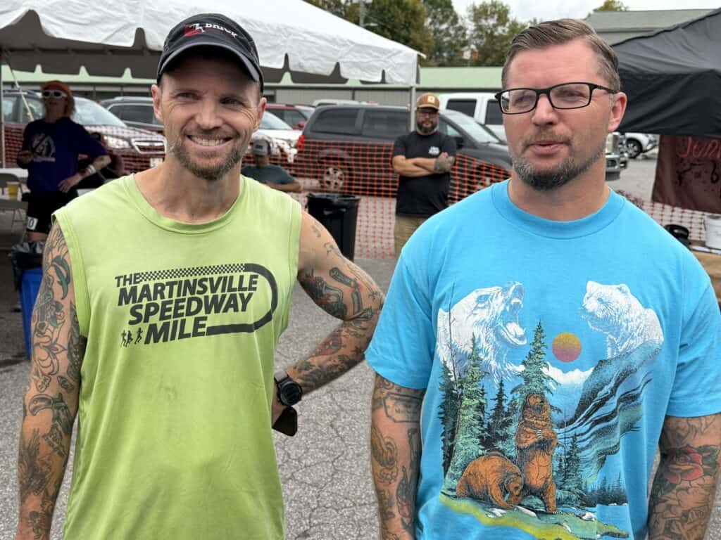 Two men with tattoos at Franklin fall family event, smiling and posing for photo.