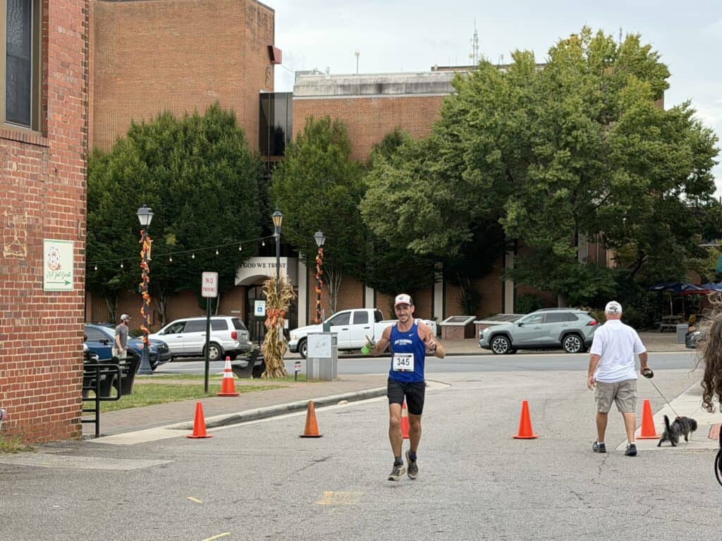 Runner crossing finish line at Franklin fall marathon event.