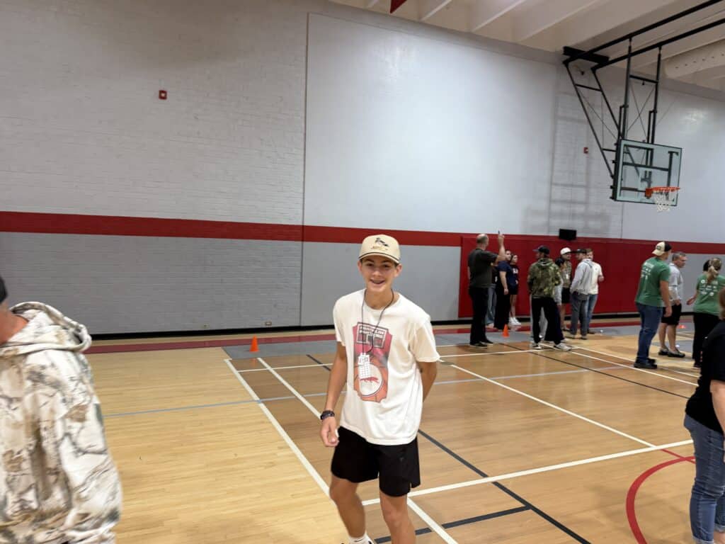 Young boy smiling in basketball gym during indoor game.