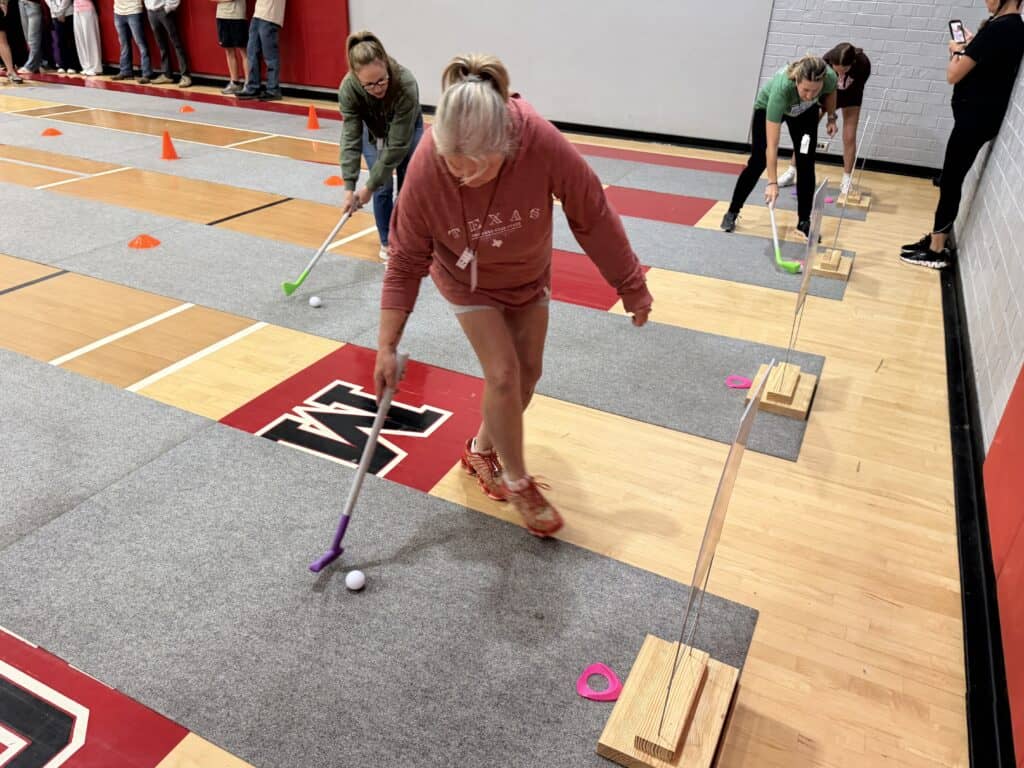 People playing mini golf indoors during Franklin fall family event.