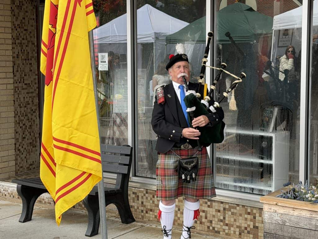Scottish bagpiper in traditional attire performing outdoors in Franklin.