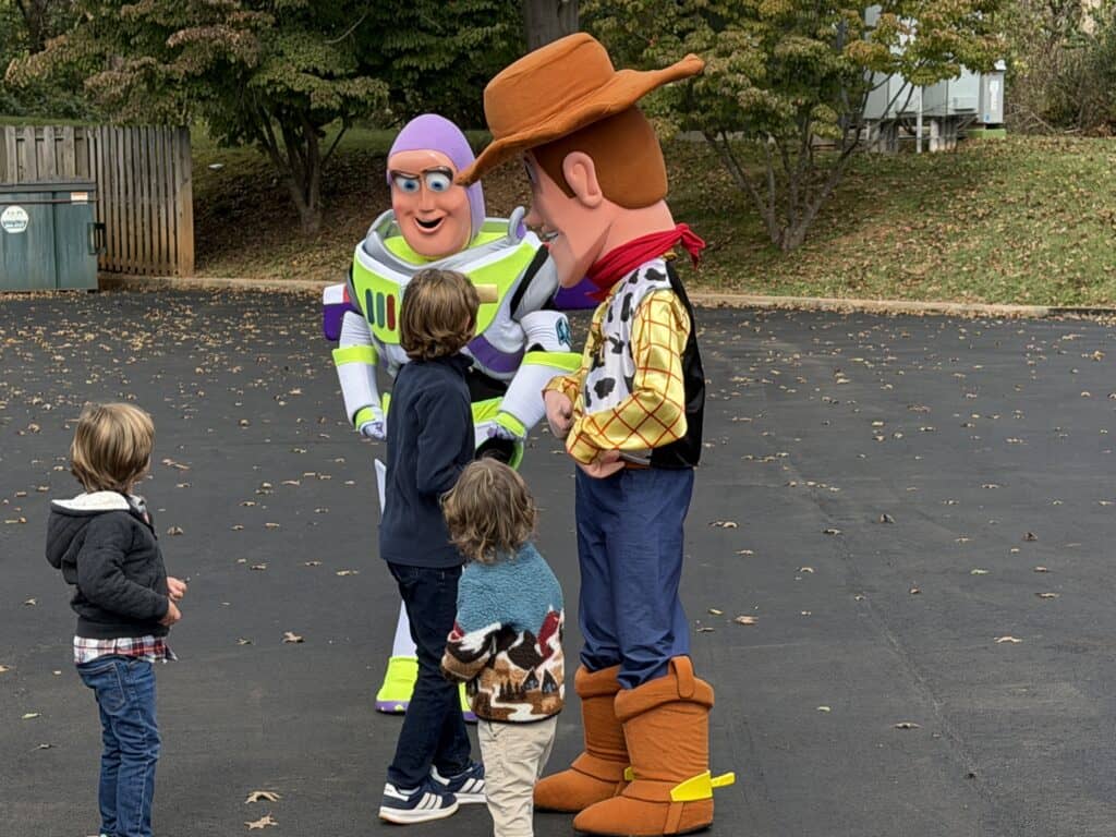 Children meet Toy Story characters in a fall outdoor setting.