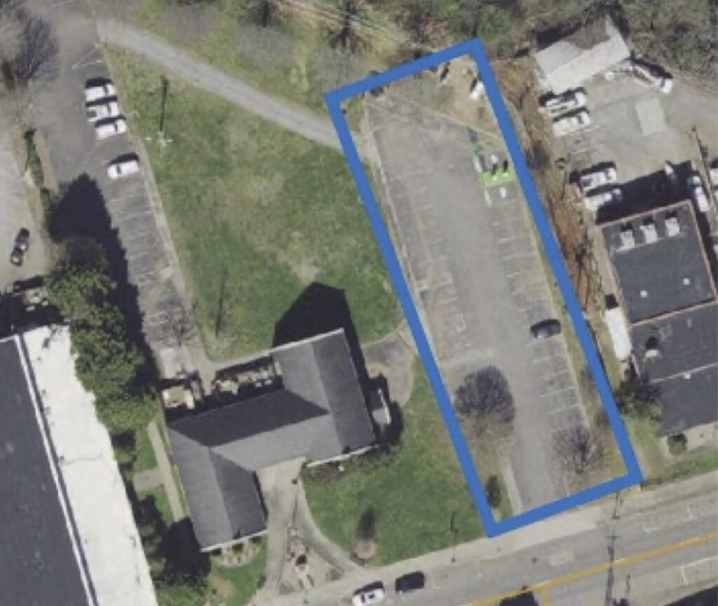 Aerial view of a parking lot outlined in blue near residential buildings.