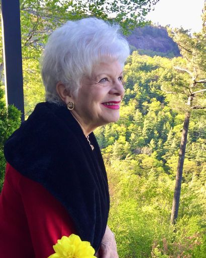 Elderly woman enjoying nature with a bright smile and white hair.