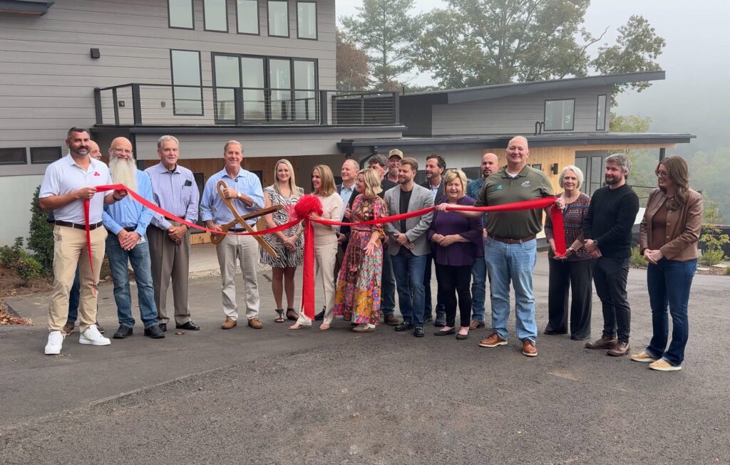 Group of people at ribbon-cutting ceremony outside modern building.