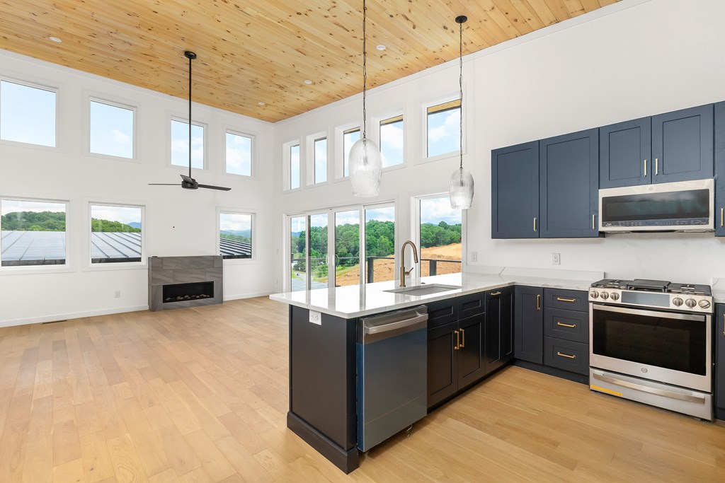 Spacious modern kitchen with large windows, navy cabinets, and island for cooking and socializing.
