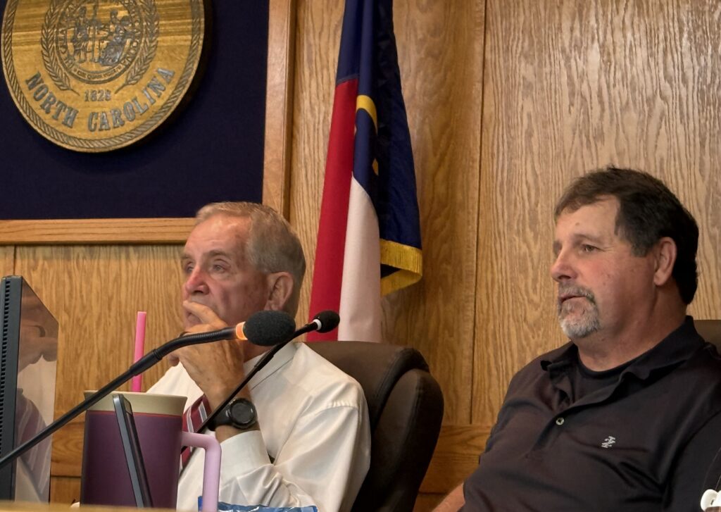 County commissioners seated at a meeting table during a public session.