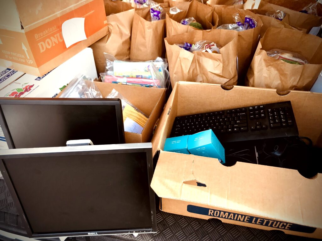 Community food distribution with paper bags and supplies for neighbors.